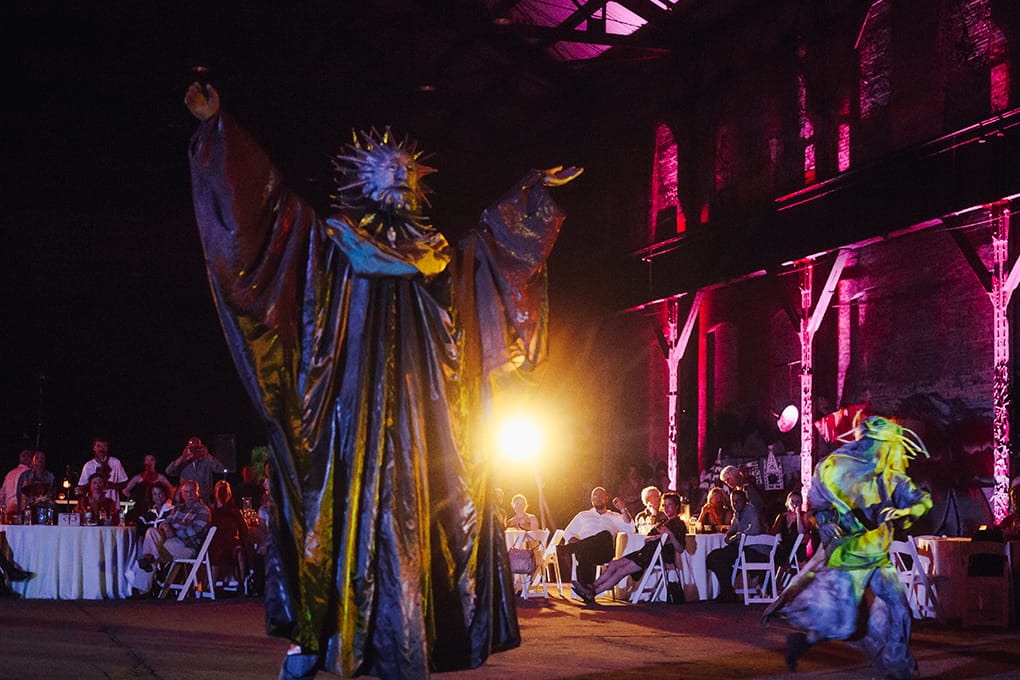A larger-than-life costumed performer entertaining guests at a warehouse event produced by Michael Willis Events
